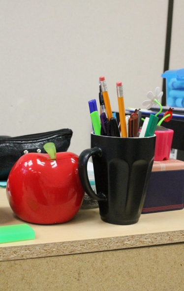 A school desk with pencils and pencil holders
